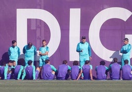 Guillermo Almada (de pie a la derecha) escucha al segundo entrenador, Darwin Quintana, dirigirse a la plantilla del Real Valladolid durante la charla a puerta cerrada este martes en los Campos Anexos.