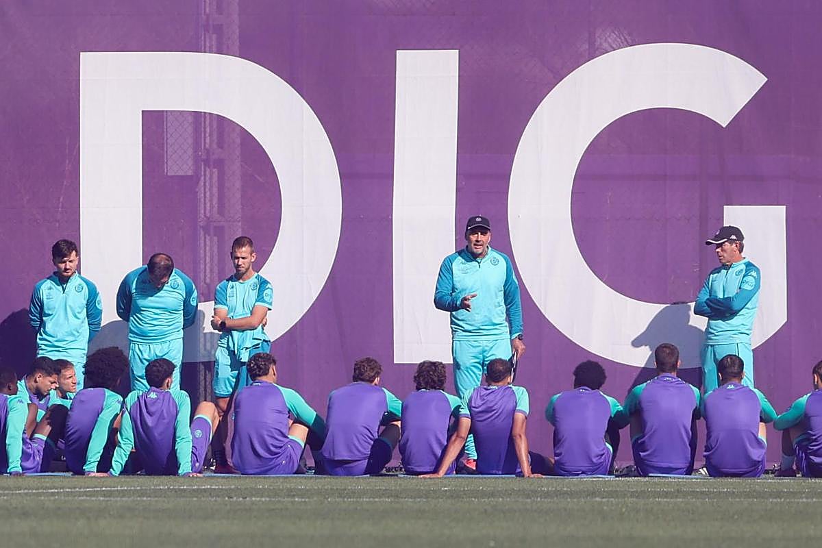 Guillermo Almada (de pie a la derecha) escucha al segundo entrenador, Darwin Quintana, dirigirse a la plantilla del Real Valladolid durante la charla a puerta cerrada este martes en los Campos Anexos.