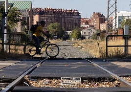 Un ciclista cruza por el paso a nivel de Argales, con la vía ya desmontada hasta la estación.