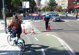 Un agente supervisa los conos del carril de giro de la avenida de Gloria Fuertes hacia la calle Arzobispo José Delicado, cortada al tráfico, antes del puente de Poniente, mientras una ciclista se topa con carril bici cerrado.