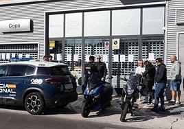 Agentes de la Policía Nacional y afectados por el cierre de Motos Copa en Valladolid delante de la tienda esta mañana.
