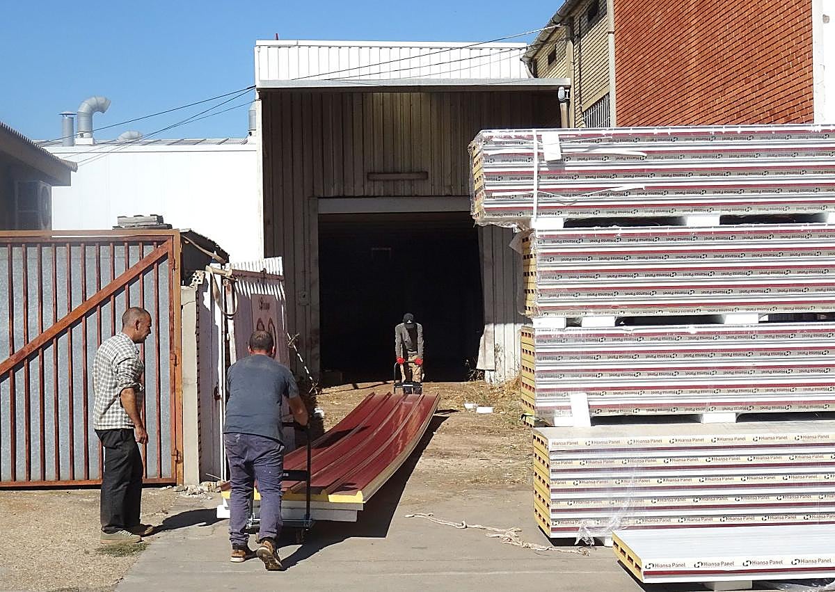 Imagen secundaria 1 - Los operarios mueven los paneles de la cubierta en las instalaciones para meterlas por el lateral de la nave. Debajo, a la izquierda, detalle del logo de la panificadora.