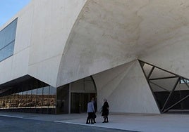 Un grupo de personas espera junto a la puerta principal de acceso del edificio CIDE, ubicado a las afueras de la ciudad.