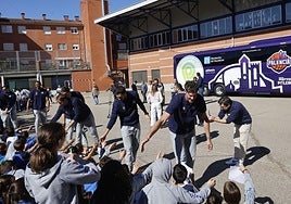 Los jugadores saludan a los alumnos de Maristas en el patio del colegio, con el autobús de fondo.
