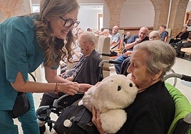 La directora del proyecto, Blanca Deusdad, acerca a Nuka a una residente para que la acaricie