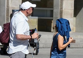 Dos personas se protegen del sol con una gorra y una chaqueta.