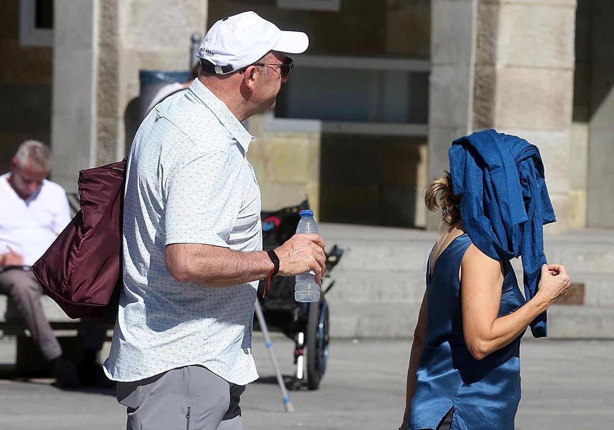 Dos personas se protegen del sol con una gorra y una chaqueta.