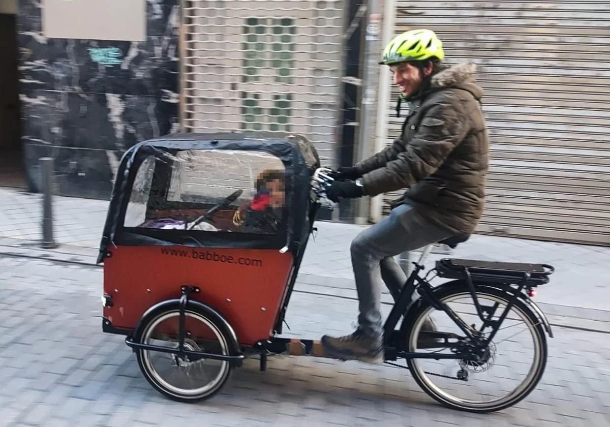 Daniel de Santiago lleva a un pasajero en su bicicleta de carga.