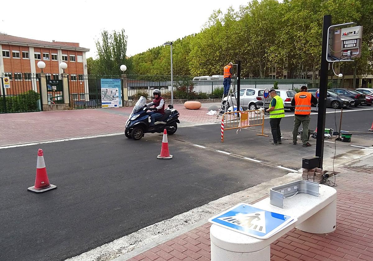 Imagen principal - Arriba, colocación del paso inteligente de Manuel Silvela y detalle del nuevo panel de la señal (debajo a la izquierda). A la derecha, la señal luminosa tradicional que marca la presencia del segundo paso de cebra aún sin pintar para peatones y ciclistas.