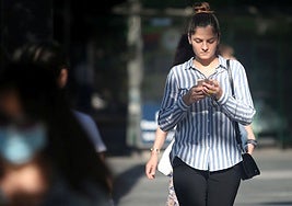 Una joven camina con su móvil.