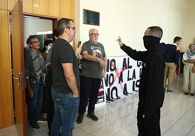 Un hombre con la cara tapada se dirige a algunos de los activistas en Derecho.