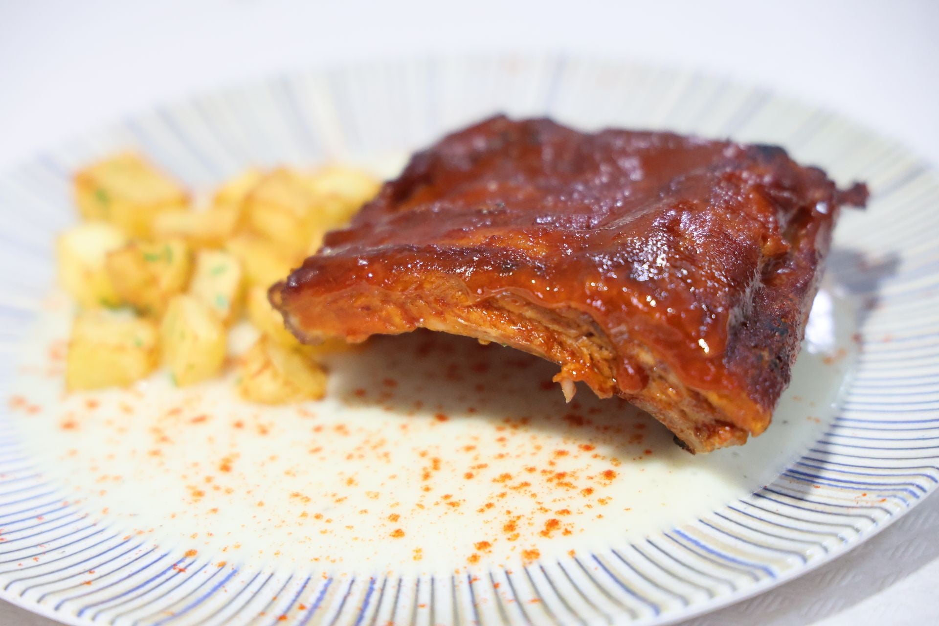 Segundo plato, costillas con salsa de barbacoa casera, parmentier de patata y patatas caseras.