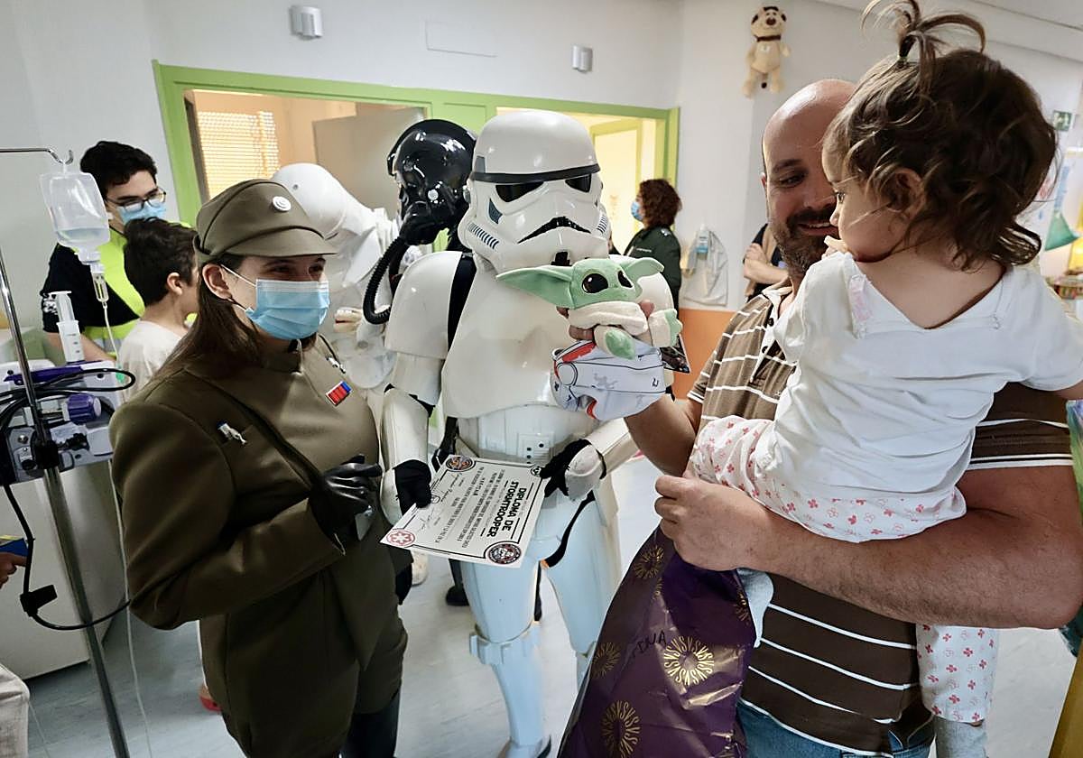 Una niña recibe un regalo y un diploma del Imperio Galáctico, de mano de los personajes de Star Wars