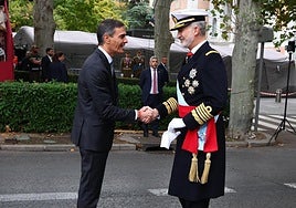 El rey Felipe VI (d) saluda al presidente del Gobierno Pedro Sánchez a su llegada al desfile de las Fuerzas Armadas con motivo de la Fiesta Nacional.