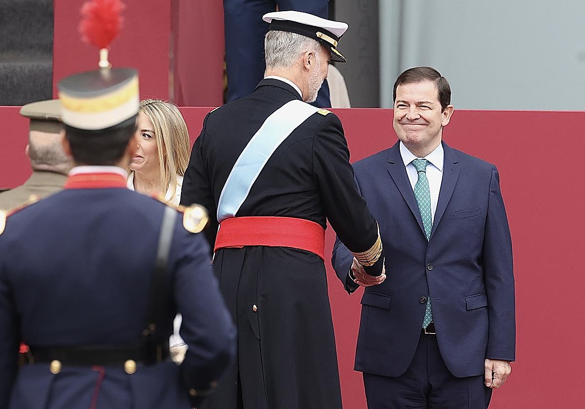 Fernández Mañueco saluda al Rey Felipe durante el acto de homenaje a la bandera nacional y al desfile militar con ocasión del día de la Fiesta Nacional.