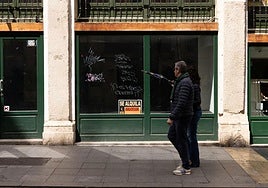 Una pareja camina por la calle Platerías de Valladolid frente a un negocio cerrado, hace unos meses.
