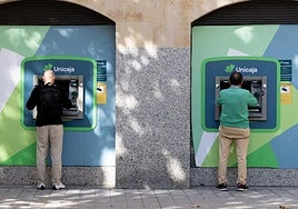 Dos ciudadanos, uno joven y otro de mediana edad, sacan dinero en sendos cajeros de la plaza de San Miguel el pasado miércoles.