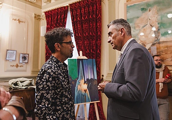 El pintor Santiago Lorenzo conversa con el presidente de los cofrades, Ricardo Fernández, ante el cuadro anunciador de la Semana Santa.