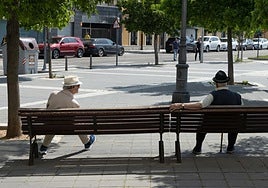Dos personas sentadas en unos bancos de la calle Recondo.