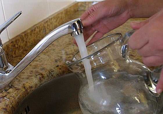 Un vecino coge agua del grifo de su casa en una jarra.