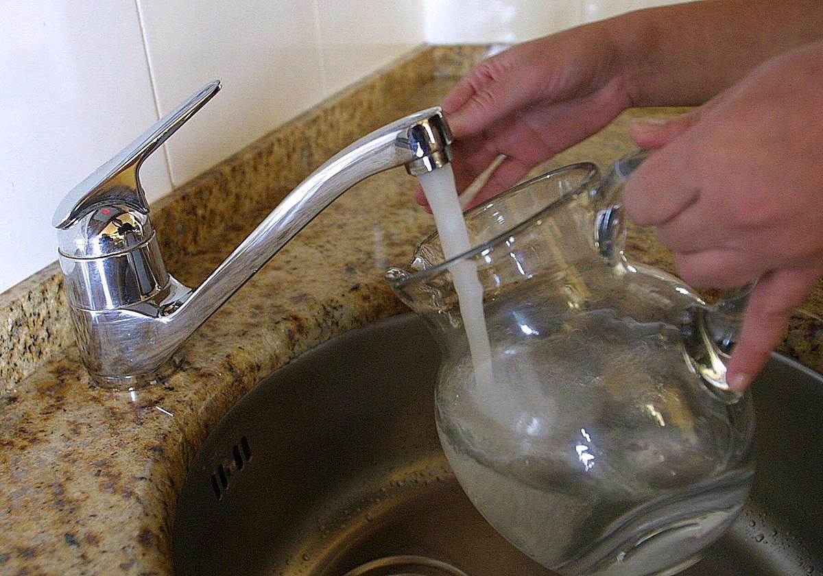 Un vecino coge agua del grifo de su casa en una jarra.