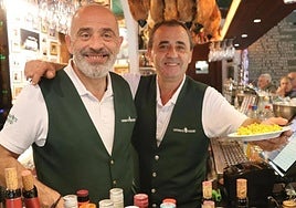 Imagen de dos de los camareros del establecimiento con la tapa de paella.