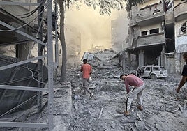 Varios hombres caminan por los escombros tras uno de los ataques lanzados ayer por Israel.