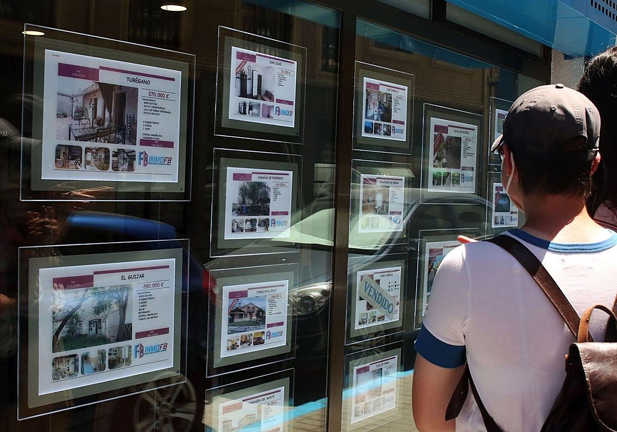 Un joven observa los anuncios de una inmobiliaria.