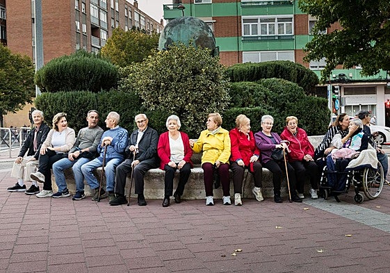 Eutiquio, Chus, Alfredo, Román, Alejandro, María Teresa, Magdalena, María Jesús, Angelines, Asunción, Violeta y Victoria, sentados en el banco de piedra bajo 'La unión del mundo'.