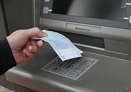 Un hombre saca dinero de un cajero automático.