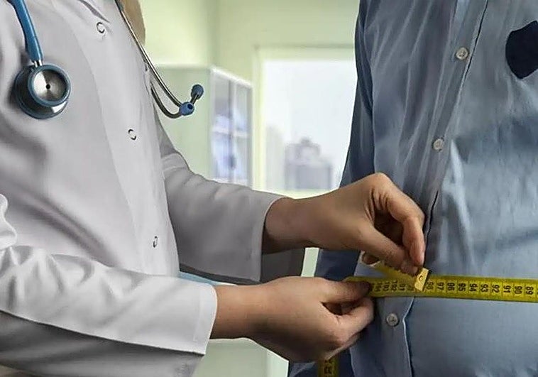 Un endocrino mide el contorno del abdomen de un paciente en la consulta.
