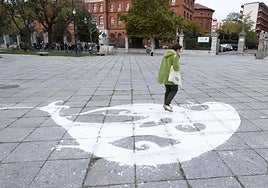 Una mujer camina junto a la paloma de la paz dibujada en la plaza de San Pablo.