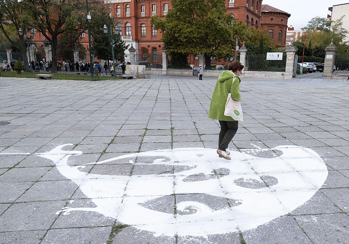 Una mujer camina junto a la paloma de la paz dibujada en la plaza de San Pablo.
