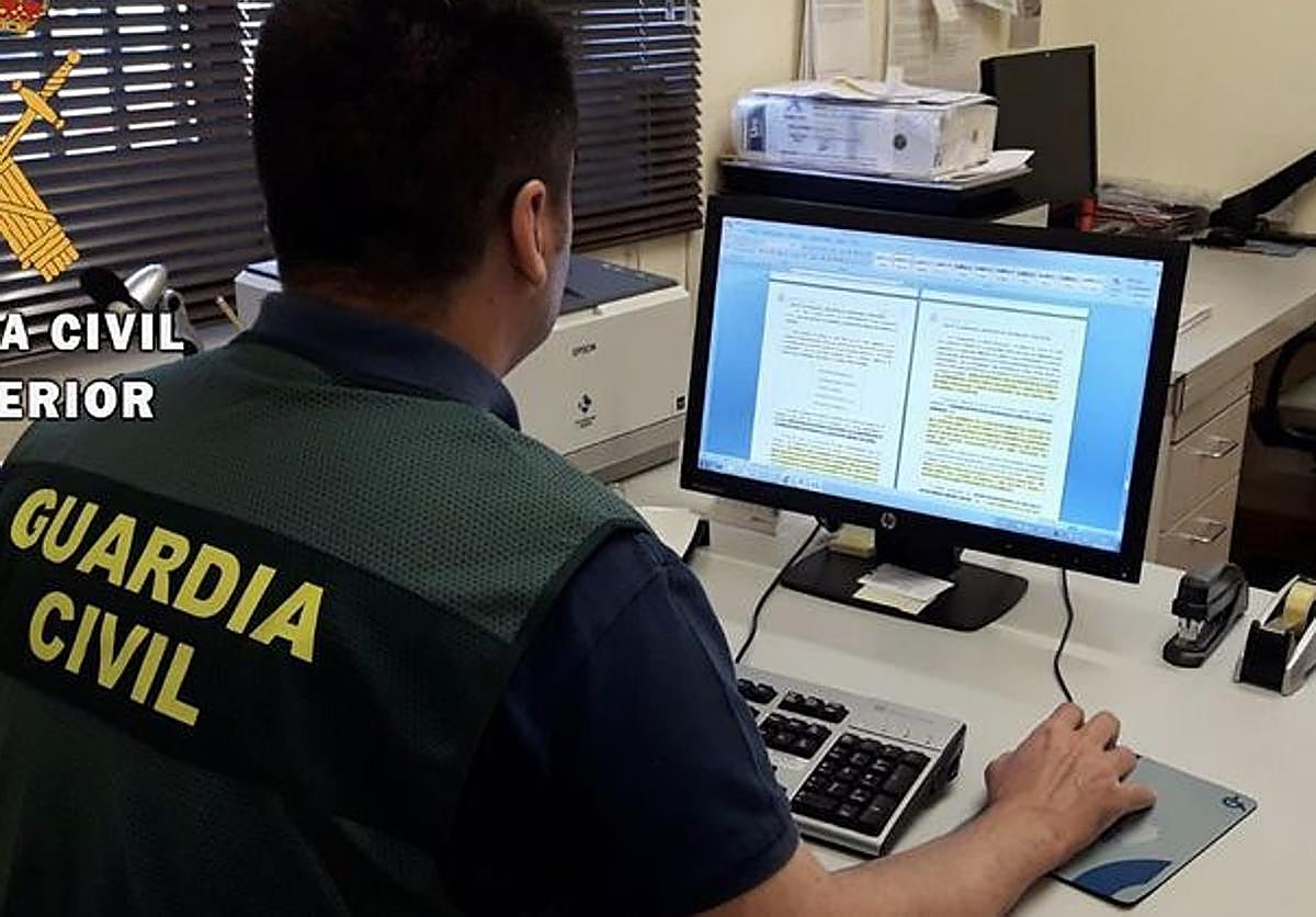 Un guardia civil examina documentación en su ordenador.