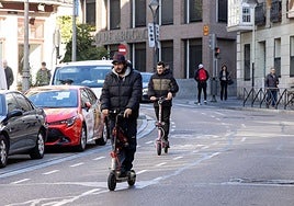 Dos usuarios de patinete eléctrico circulan por la calle Angustias.