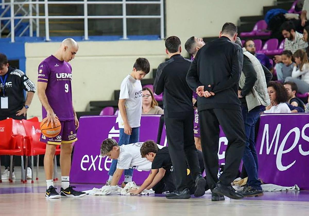 Dos chicos de la cantera se afanan para secar la zona más encharcada por las goteras del pabellón Pisuerga.