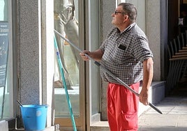 Un trabajador limpia los cristales de un escaparate.