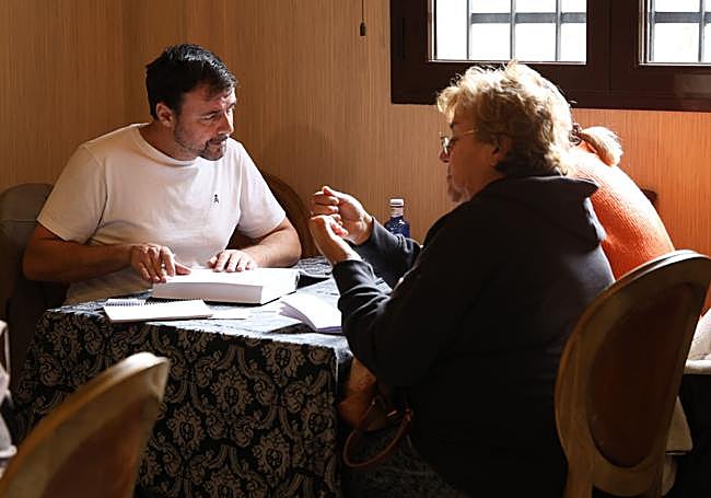 Marcos Martín Quiroga atiende a dos clientas libro de reservas en mano.