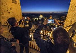 Turistas sacan fotos en una visita nocturna a la torre de la Catedral de Segovia.