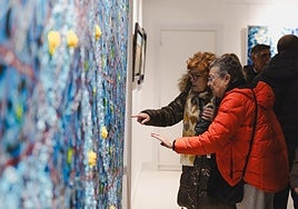 Dos personas observan una de las obras de la exposición del Ateneo.