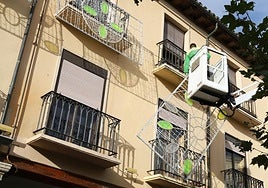 Un operario coloca los elementos ornamentales en los balcones de la Plaza Mayor.