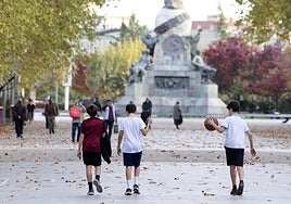 Tres escolares juegan a primera hora de la tarde de este miércoles en los campos de Recoletos recubiertos de una alfombra de hojas caídas.
