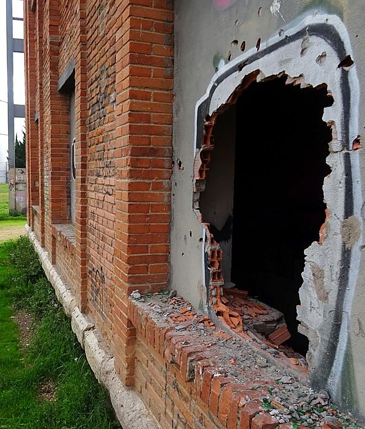 Imagen secundaria 2 - Arriba, las palomas sobrevuelan el inmueble del ala sur de la azucarera Santa Victoria. Debajo, a la izquierda, el frontal en el que se abierto el boquete en una de sus ventanas sobre la 'O' de un grafiti y detalle (derecha) del agujero.
