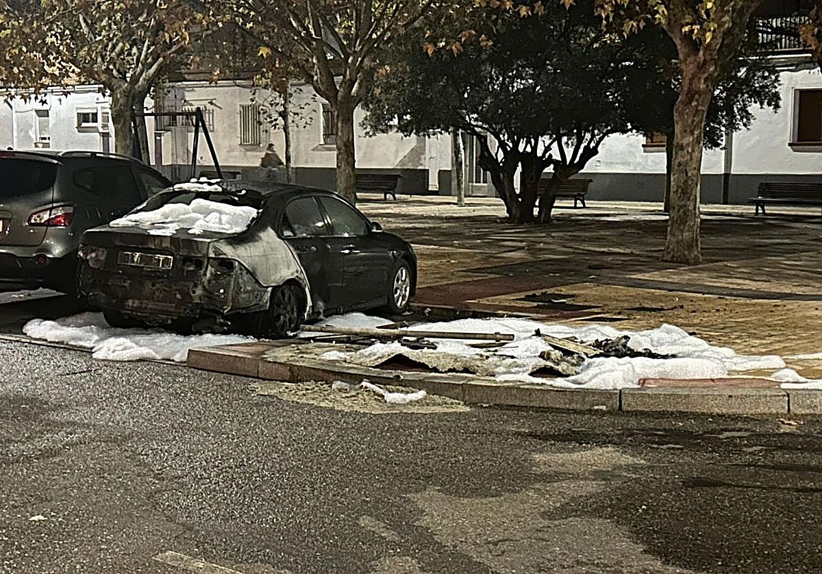 Coche dañado por el incendio con los restos de espuma tras la intervención de los bomberos en Amor de Dios.