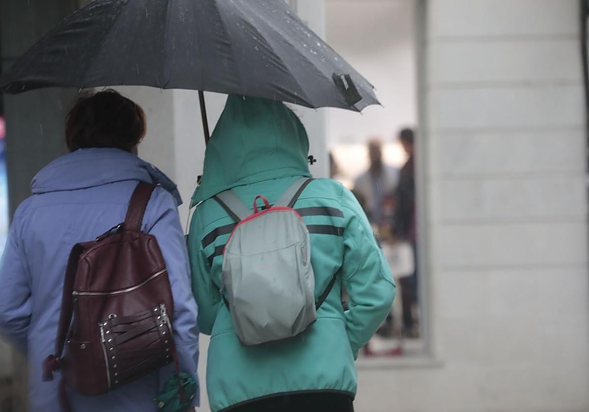 Dos viandantes se protegen de la lluvia y el fuerte viento en una imagen de archivo.