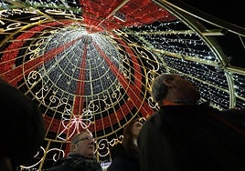 Vecinos de la ciudad pasean bajo el árbol de Navidad de la Plaza Mayor.