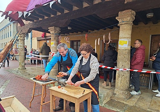 Dos vecinos colaboradores se afanan en hacer chorizos de forma tradicional
