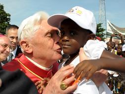 El Papa besa a un niño antes de oficiar una misa para los obispos y sacerdotes angoleños en la iglesia de San Pablo. / EFE