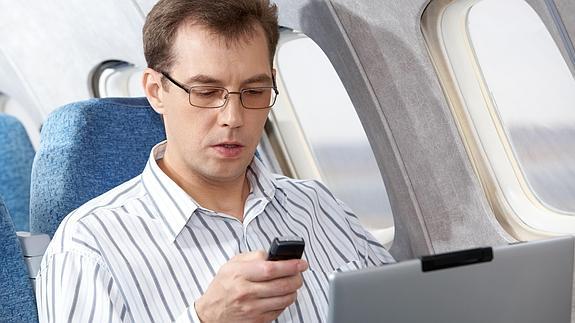 Un joven con un móvil en un avión.
