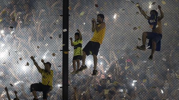 Hinchas del Boca Juniors trepan por una de las vallas de La Bombonera. 